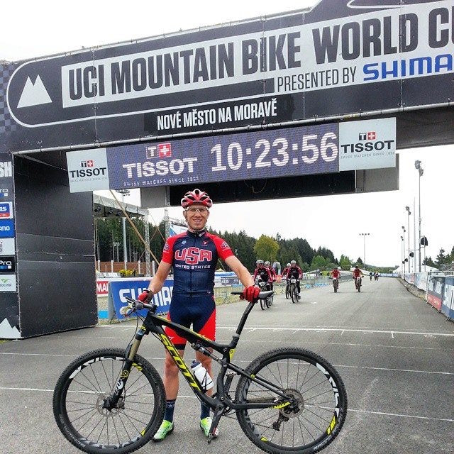 Cyclist celebrating at the finish line of a UCI World Cup mountain bike race with Tissot branding.