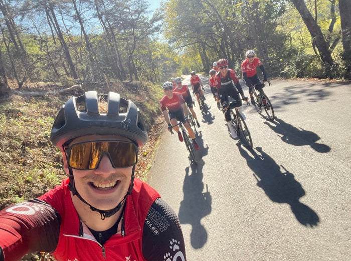Road cyclists riding in a group on a back road wearing Otterhaus Coaching uniforms.