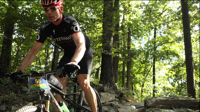 Person mountain biking on a rocky trail in a forest