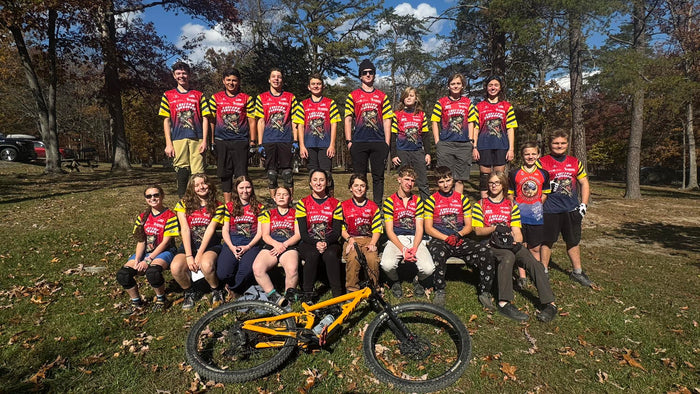 Group of High School Mountain Bikers in matching jerseys posing with mountain bike.